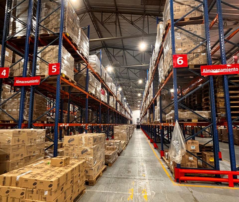 Pasillo de racks con mercadería en el almacén de QS Consumo